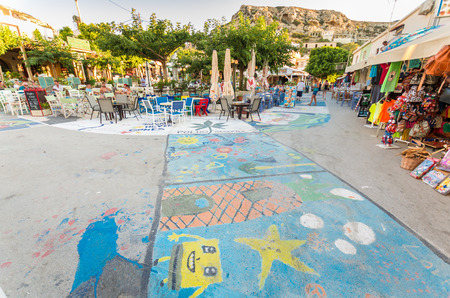 MATALA, CRETE ISLAND, GREECE - JUNE 30: Tourists relax on the streets of Matala in south of Creta. The streets are painted.のeditorial素材