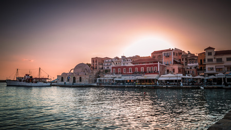 CHANIA, CRETE ISLAND, GREECE - JUNE 26, 2016: View of the old venetian port of Chania on Crete island, Greece. Tourists relaxing on promenade.のeditorial素材