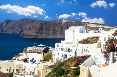 Oia Village, Santorini Cyclade islands, Greece. Beautiful view of the town with white buildings, blue church's roofs and many colored flowers.の写真素材