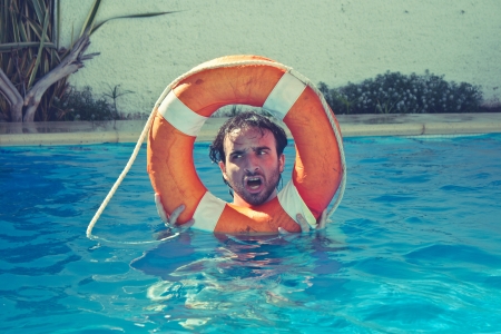 man in a swimming pool holding a life-saverの写真素材