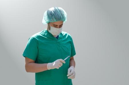 Surgeon in green scrubs holding tweezersの写真素材