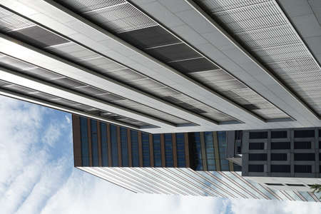 Two modern office buildings with their facades facing sunshine in upward perspective.
