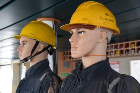 Two dummies in helmets ready to be exposed on the bridge of container vessel passing Gulf of Guinea,...