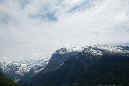 Alpine slopes partly covered with snow in springtime in Engelberg region canton Obwalden in Switzerland. The mountain range is on the background of the overcast sky.の写真素材