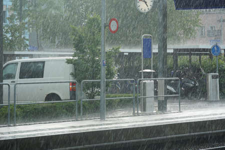 Railway station platform in the rain in Kreuzlingen, Switzerland. Heavy sheets of rain of sudden...