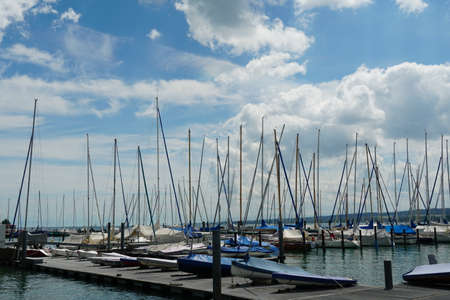 Marina with plenty of yachts and small boats covered with canvas in Lake Constance or Bodensee near...