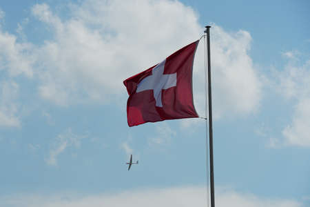 Flapping flag of Switzerland displays a white cross in the centre of a square red field. Flag is...