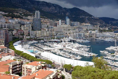 Monte Carlo with its marina and rocky hills on the background. The threatening dark clouds pull over the city.のeditorial素材