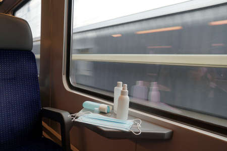 New normal concept in commuting and traveling by train. Face masks and hand sanitizers are...