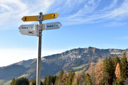 Signposts of hiking trails in region Amden in Switzerland. On the background there is autumn landscape with trees and mountains.の写真素材
