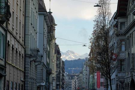 Street in the city center of Lucerne. The buildings bordering both sides of the street diminish in the perspective. There are Alp mountains on the horizon above the city.のeditorial素材
