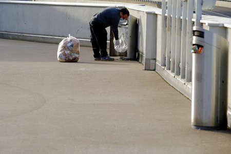 Wallisellen, Switzerland - 02 22 2021: Man changing plastic garbage bags in public garbage cans or trash cans.のeditorial素材