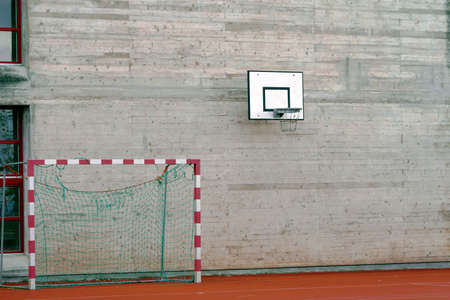 Cement wall with a basketball hoop and handball goal on the ground beside it.の写真素材