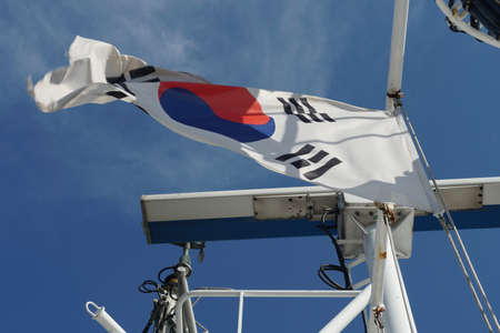 South Korean flag flapping on white mast of a merchant container ship with marine radar scanner in monkey radar island  during clear blue sky in summer day with copy space.の写真素材
