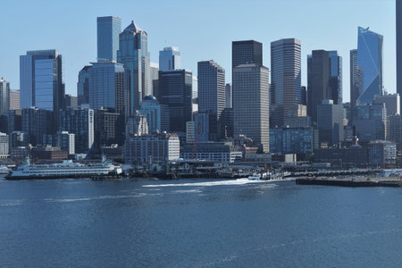 City skyline of Seattle and passenger ferry in port situated on Puget Sound with skyscrapers, view from container vessel sailing from cargo terminal to pacific ocean during sunny autumn weather.のeditorial素材