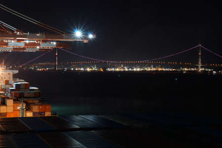 Night view from container terminal with gantry cranes and ships in port on illuminated suspension Yi Sun-sin Bridge. The bridge connects Gwangyang with Myodo-dong.の写真素材