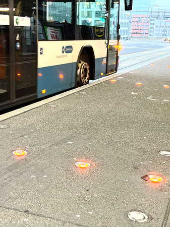 Zurich, Switzerland 12 15 2021 Public transportation bus at bus stop. There are red lights on the ground preventing the bicycles to ride on the sidewalk when there is a bus and people get on and off.の写真素材