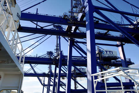 Close up view on blue gantry cranes operated by stevedores in horizontal position over white...