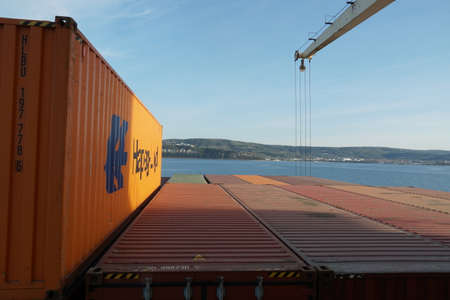 Koper, Slovenia - 04 16 2022: Orange container from Hapag Lloyd shipping company is loaded  on top...