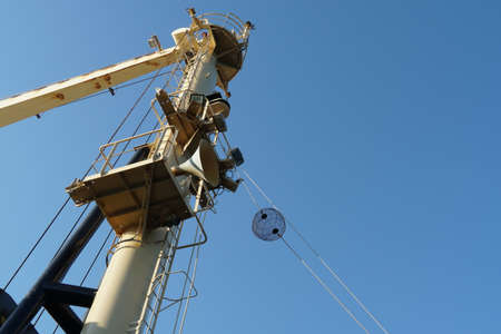 View on forward vessel mast with one black anchor ball. There are also jib of ship's crane, ladder...