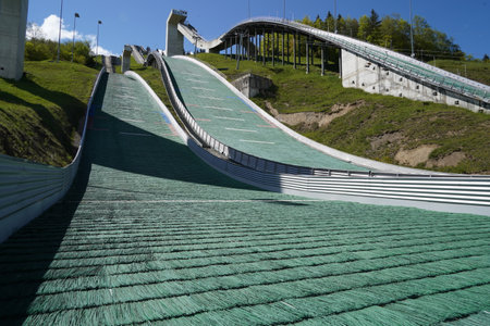 Close view on landing area of National Ski jumping venue of Switzerland in Eschbach, Einsiedeln surrounded by green forest under blue sky during summer time.の写真素材