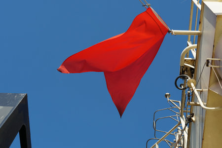 Red flag, international maritime signal flag, flying on the navigational mast of merchant vessel....