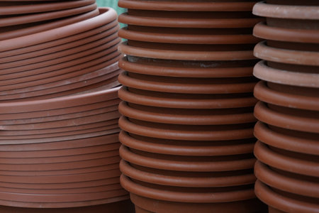 Plastic plant pots and trays stocked making out a background. They are of different shades of brown color. It is a cutout of a gardening or plant cultivation scene.の写真素材