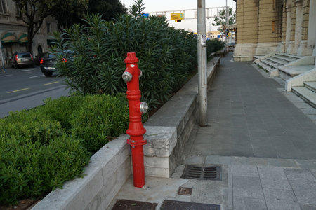 Water hydrant in red color. Firefighting equipment and water source placed on the street, footpath...