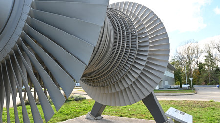 View on low-pressure turbine rotor with shrouded and standing blades used in nuclear power plant in front of main building. Blades are produced from special alloy.の写真素材
