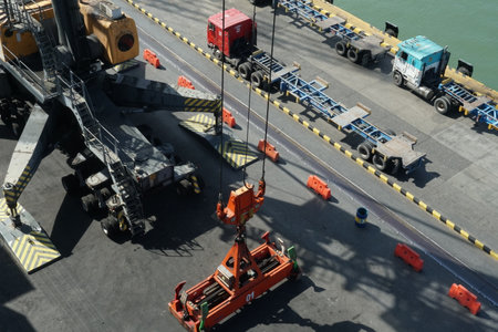 Mobile cranes with orange spreader operated by stevedores in Guatemala container terminal. In right...