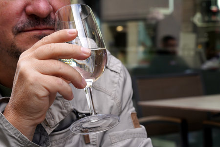 A partly visible indefinable man which hand is holding a wine glass with water and a slice of lemon...