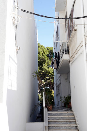 Residential house captured in vertical side view. White colored building is accessed by steps. There are shutters on the windows and a small balcony.の写真素材