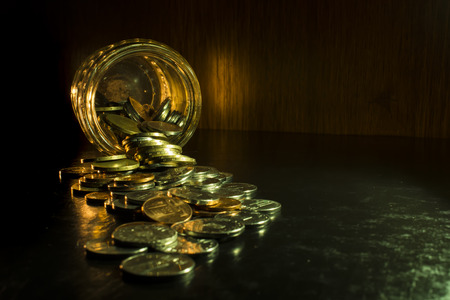 Coins in a jar isolated on black  backgroundの写真素材