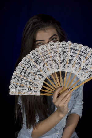 Young woman  with lace fan ,studio portrait on black backgroundの写真素材