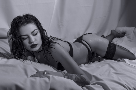 Young woman posing in black lingerie on bed ,B&Wの写真素材