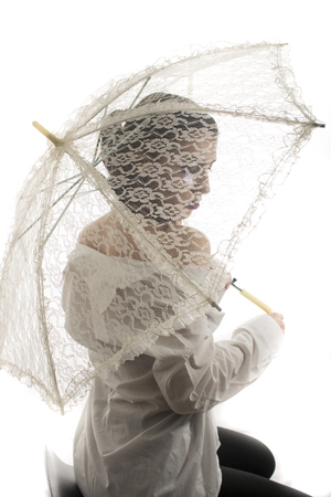 Young girl hiding behind lace umbrellaの写真素材