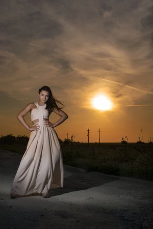Young girl at sunset wearing a long white dressの写真素材
