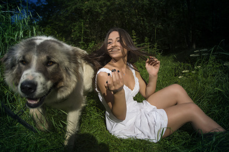 Young girl in white dress posing in a grass fieldの写真素材