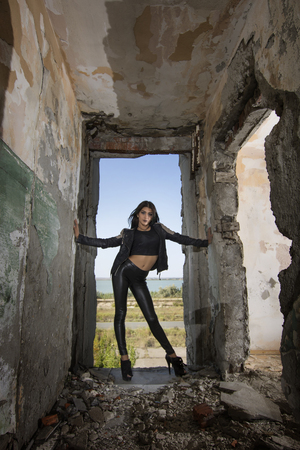 Young girl wearing leather jacket and pants posing in an old buildingの写真素材