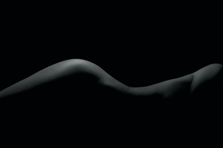 Silhouette of a body part , nude woman isolated on black backgroundの写真素材