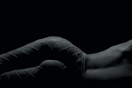 Silhouette of a body part , nude woman with fishnets on black backgroundの写真素材