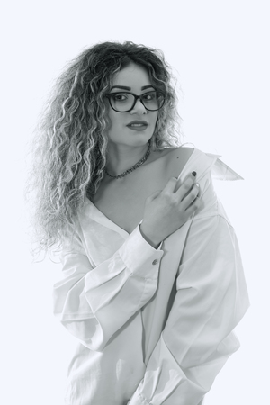 Woman with curly hair and white shirt posing on white backgroundの写真素材