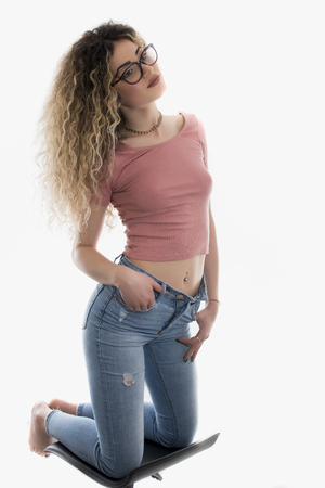 Woman with curly hair posing in t-shirt and jeans on white backgroundの写真素材
