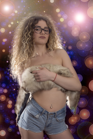 Woman with curly hair posing in jeans and fox fur on black backgroundの写真素材