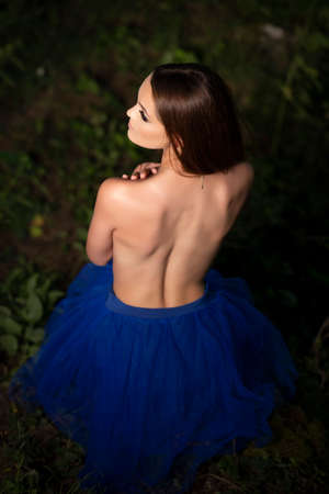 Young girl posing in a blue dress on forest background