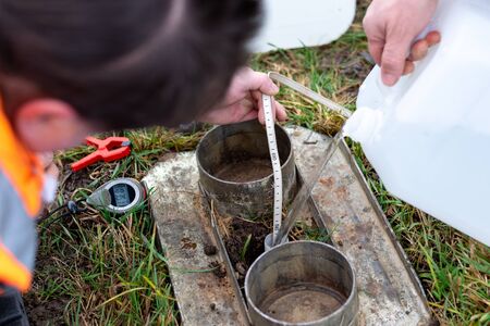 manual worker measuring level of water in drill while doing water permeability test