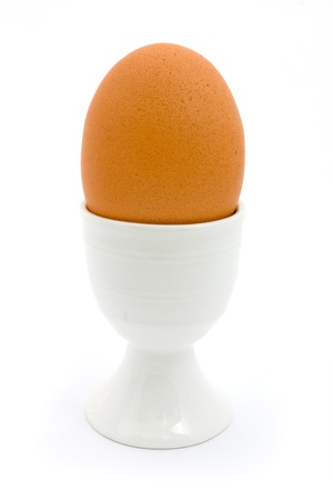 Boiled egg in white ceramic egg cup isolated over whiteの写真素材