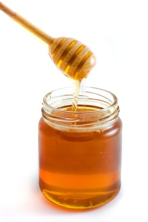 Honey dripping into jar isolated over whiteの写真素材