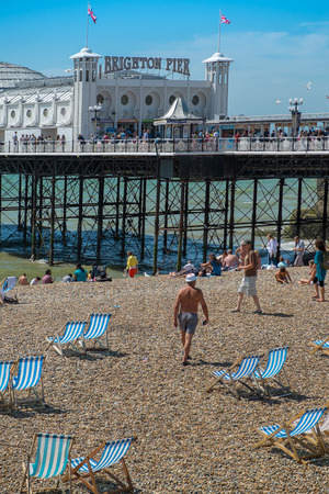 BRIGHTON, UK- JULY 28, 2013: People enjoying a rare sunny day on Brighton Beach in front of the famous Pier on July 28th, 2013.のeditorial素材
