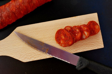 Chorizo on the wood with knife on the black background, overhead horizontal viewの写真素材